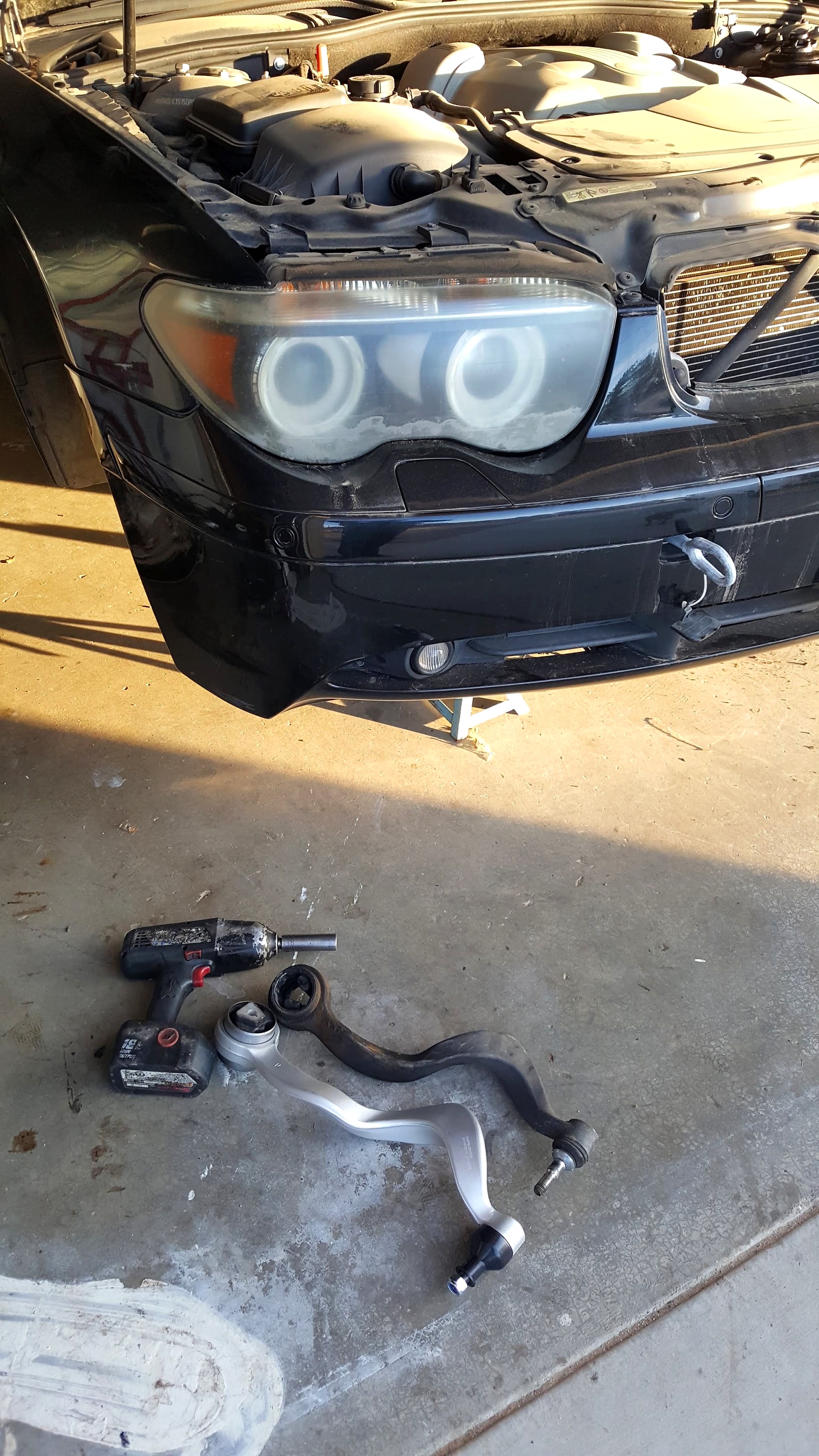 Black BMW 7 Series up on stands with its front control arm out on the garage floor